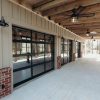 A building with large glass doors, a brick base, and a wooden ceiling with a fan.